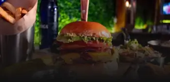 there is a hamburger and fries on a table with a bottle of beer