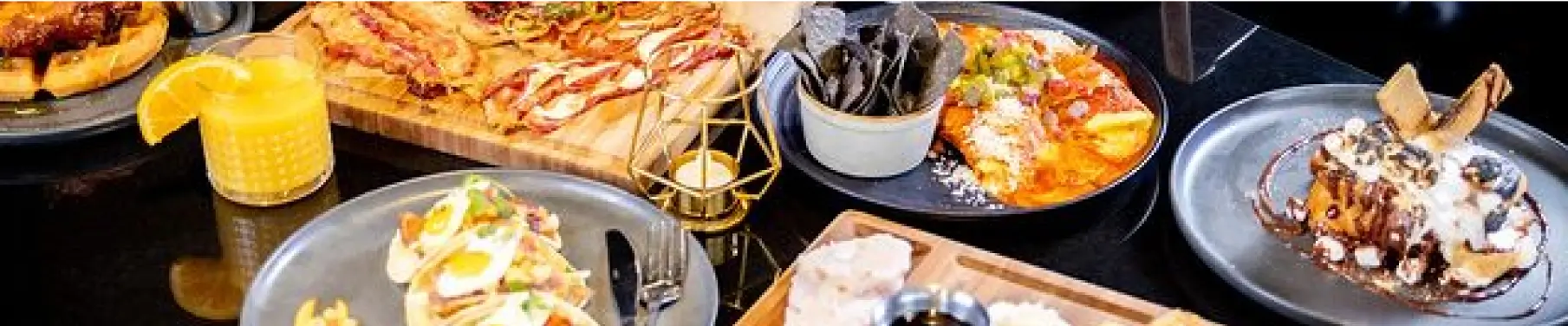 several plates of food are on a table with a glass of orange juice